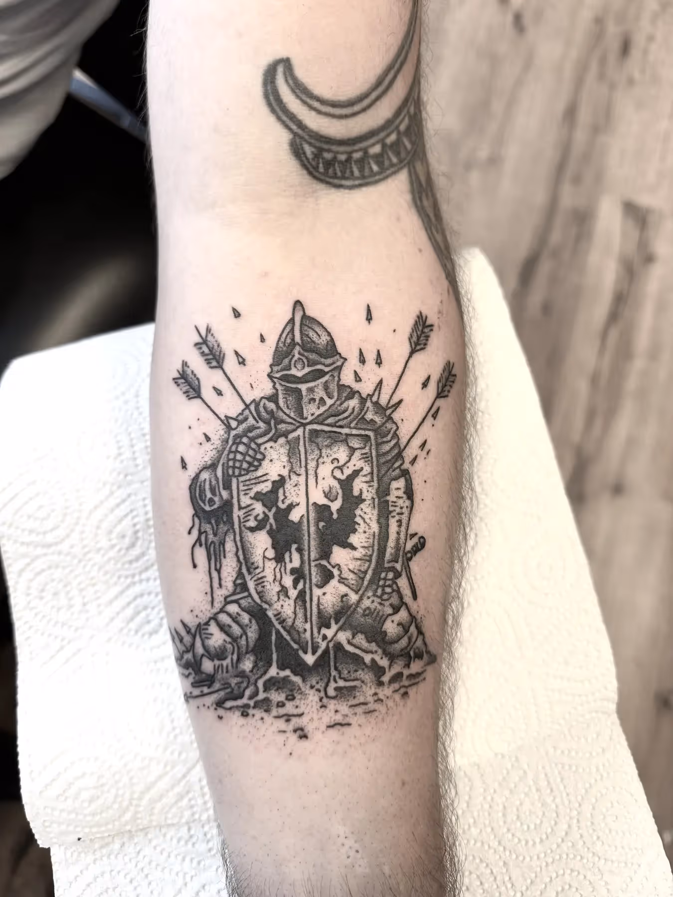 Black and grey tattoo van een ridder met schild en pijlen op onderarm, gezet door Nik Mart bij True Spirit Tattoo Barendrecht