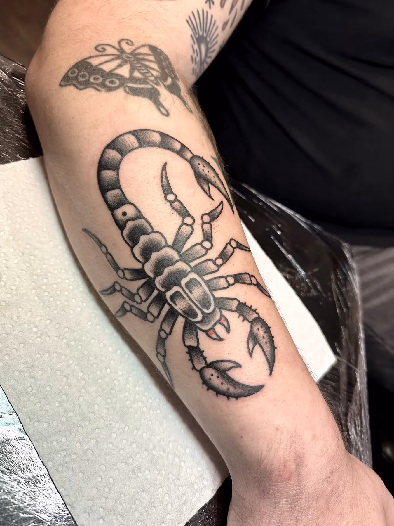 Black and grey traditional schorpioen tattoo op onderarm, gezet door Nik Mart bij True Spirit Tattoo Barendrecht